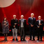 Na scenie stoją Laureatki i Laureaci Nagród 100-lecia ZAIKS-u. Od lewej: Szymon Safjan (w imieniu Marka Safjana), Grażyna Miśkiewicz (w imieniu męża – Henryka Miśkiewicza), Maciej Buszewicz, Ernest Bryll, Sławek Wierzcholski, Andrzej Dąbrowski, Marek Dutkiewicz. Fot. Karpati & Zarewicz.